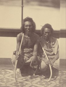 Portrait of Two Native Men Sitting on a Boat Holding Long Curved Sticks